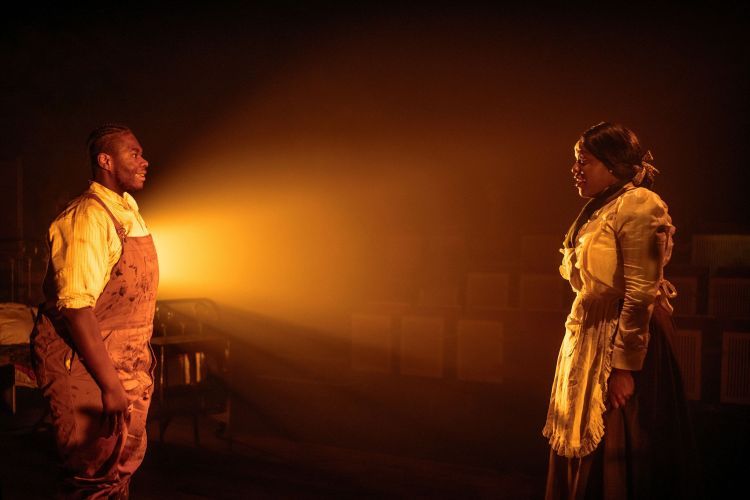 Two actors look at one another across the set